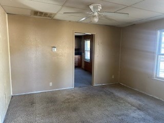 carpeted spare room with ceiling fan, plenty of natural light, and a paneled ceiling