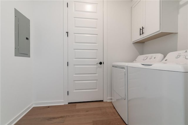 laundry room with cabinets, independent washer and dryer, electric panel, and light hardwood / wood-style flooring