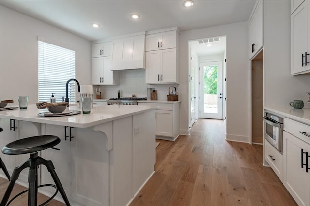 427 E Martin Luther King Jr Blvd, Fayetteville, AR 72701 - kitchen featuring a breakfast bar, stainless steel oven, white cabinets, light countertops, and recessed lighting