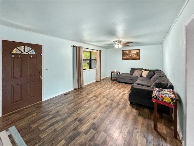 living room featuring ceiling fan, ornamental molding, and dark wood-type flooring