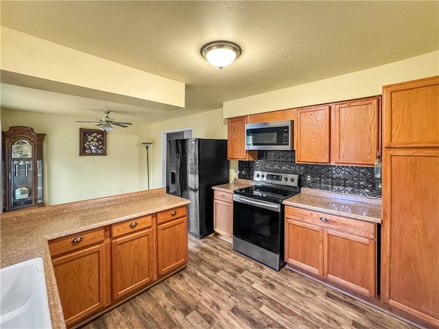 kitchen with ceiling fan, sink, tasteful backsplash, appliances with stainless steel finishes, and hardwood / wood-style floors