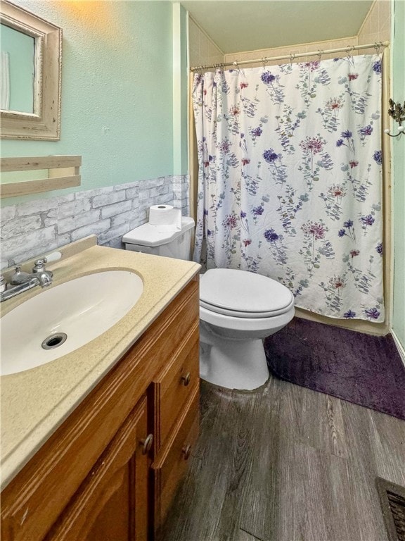 bathroom with tile walls, curtained shower, vanity, hardwood / wood-style flooring, and toilet