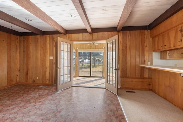 interior space featuring french doors, ceiling fan, wood walls, and beam ceiling