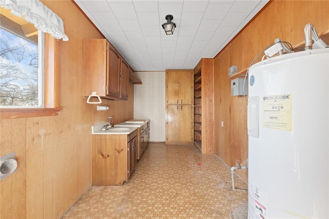 kitchen with sink, electric water heater, and wood walls