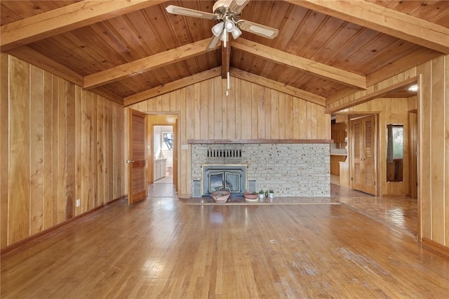 unfurnished living room with ceiling fan, wooden walls, light hardwood / wood-style flooring, wooden ceiling, and a fireplace