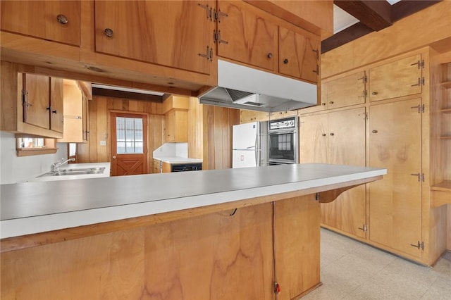 kitchen featuring beam ceiling, sink, white refrigerator, kitchen peninsula, and wood walls