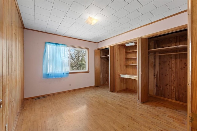 unfurnished bedroom featuring light wood-type flooring, ornamental molding, and a closet