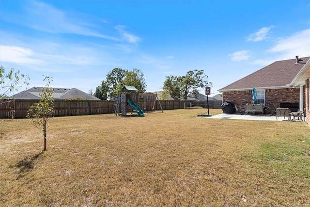 view of yard featuring a patio area, a fenced backyard, and a playground