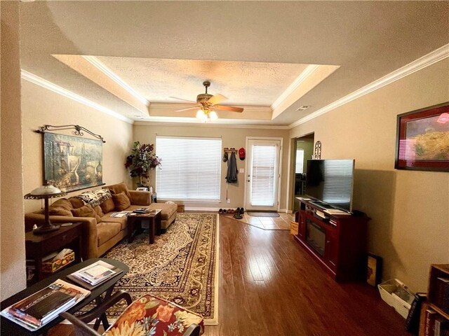 living room with crown molding, a textured ceiling, a raised ceiling, hardwood / wood-style flooring, and ceiling fan