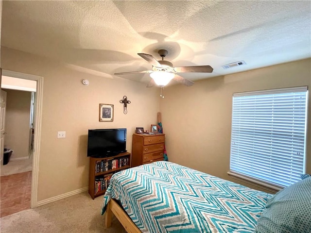 bedroom featuring light carpet, a textured ceiling, and ceiling fan