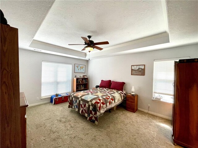 carpeted bedroom with a tray ceiling, a textured ceiling, and ceiling fan