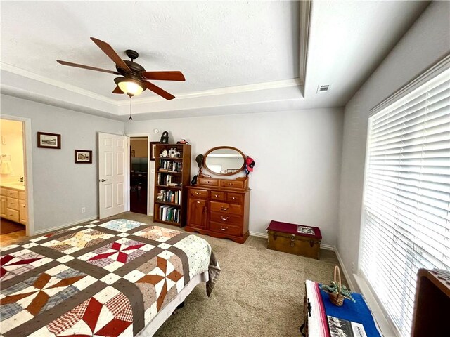 bedroom with ceiling fan, ensuite bath, a tray ceiling, and carpet