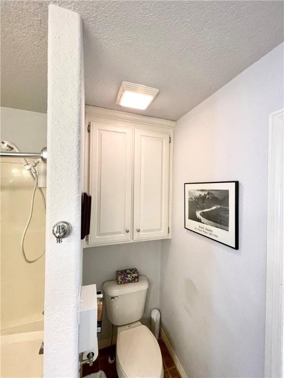 bathroom featuring a shower, a textured ceiling, and toilet