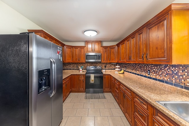 kitchen with light stone countertops, sink, appliances with stainless steel finishes, and backsplash