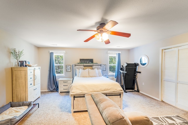 carpeted bedroom with a textured ceiling, a closet, and ceiling fan