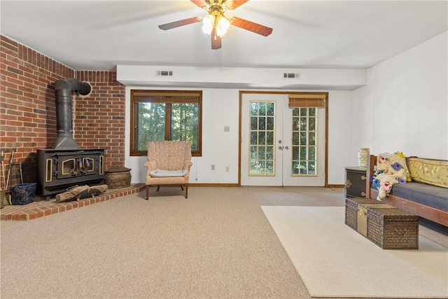 sitting room with ceiling fan, french doors, light carpet, and a wood stove