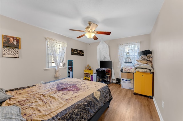 bedroom with ceiling fan, light wood-type flooring, and multiple windows