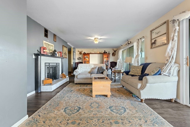 living room with dark hardwood / wood-style flooring and a brick fireplace