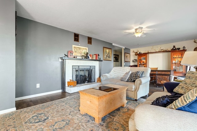 living room featuring dark hardwood / wood-style flooring, a brick fireplace, and ceiling fan