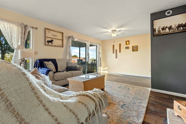 living room with a textured ceiling, dark hardwood / wood-style flooring, and ceiling fan