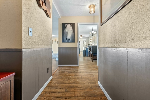 hall with a textured ceiling and dark hardwood / wood-style floors