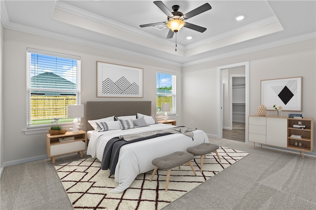 carpeted bedroom with ceiling fan, crown molding, multiple windows, and a walk in closet