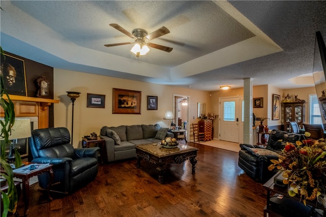 living room with a tray ceiling, ceiling fan, plenty of natural light, and dark hardwood / wood-style floors