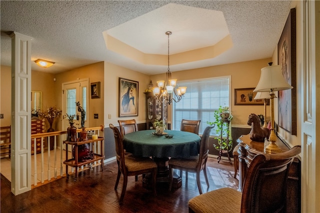 dining space with a tray ceiling, dark hardwood / wood-style flooring, a chandelier, and french doors