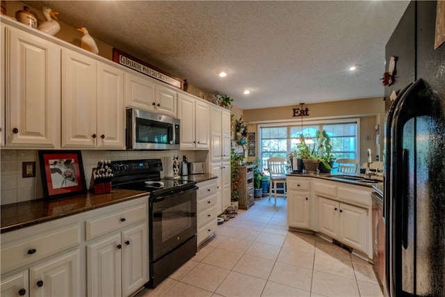 kitchen featuring white cabinets, backsplash, hanging light fixtures, and black appliances