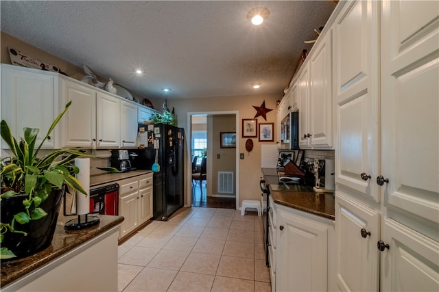 kitchen featuring white cabinets, light tile patterned floors, a textured ceiling, and appliances with stainless steel finishes