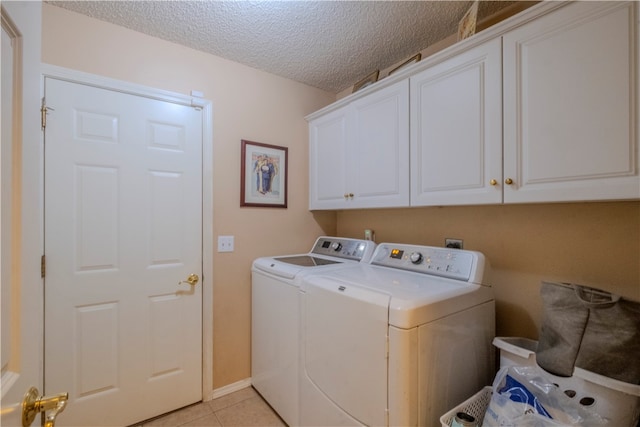 laundry area with light tile patterned flooring, cabinets, a textured ceiling, and independent washer and dryer