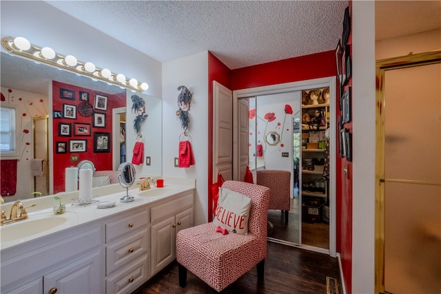 bathroom with hardwood / wood-style floors, vanity, a textured ceiling, and walk in shower