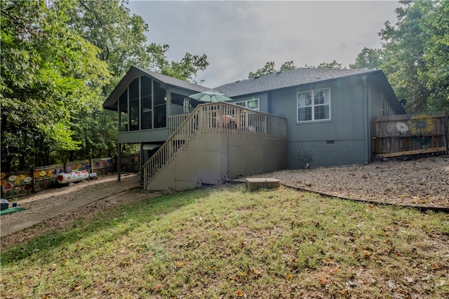 rear view of property featuring a sunroom, a yard, and a wooden deck