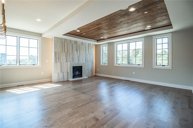 unfurnished living room featuring wood-type flooring, a tray ceiling, plenty of natural light, and wooden ceiling