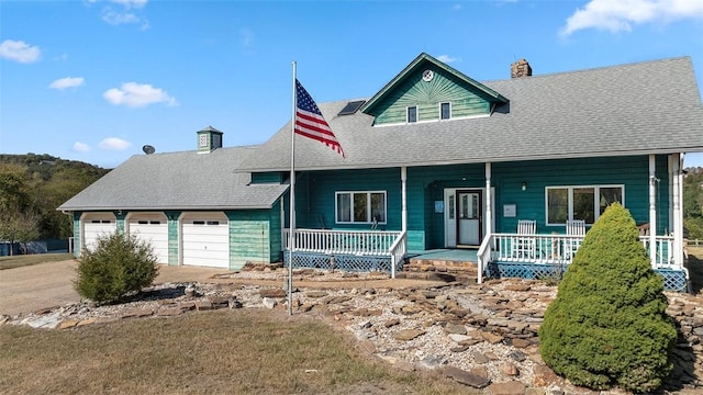 view of front facade featuring roof with shingles, a porch, driveway, and a chimney