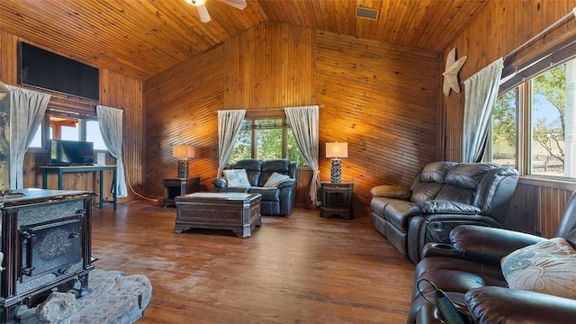 living room with a wood stove, ceiling fan, wooden ceiling, wood walls, and wood finished floors