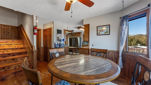 dining space with a textured ceiling, wood finished floors, a ceiling fan, and stairway