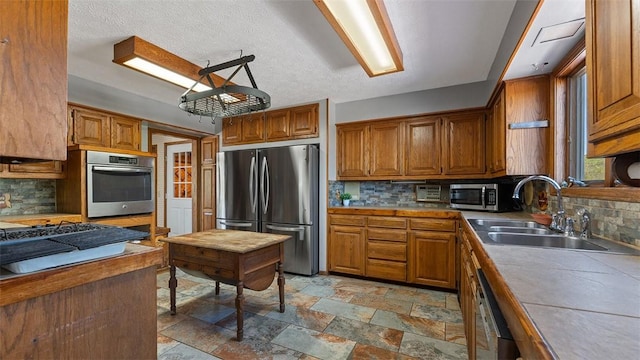 kitchen with a sink, backsplash, brown cabinetry, and stainless steel appliances