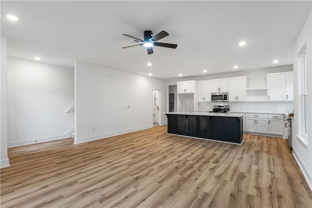 kitchen with white cabinetry, light hardwood / wood-style floors, appliances with stainless steel finishes, and a kitchen island with sink