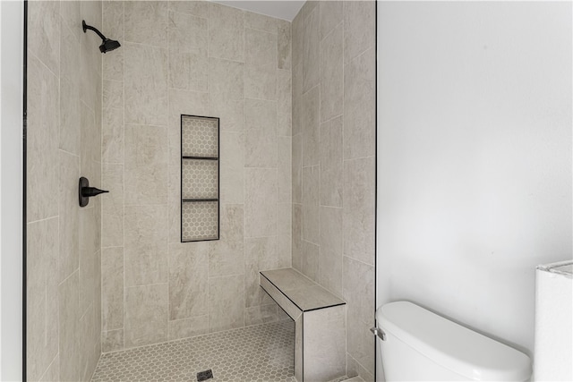 bathroom featuring a tile shower and toilet