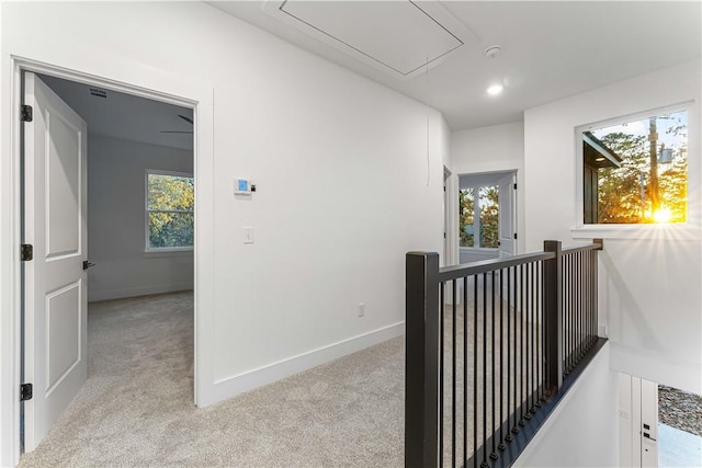 hallway with baseboards, carpet, attic access, and an upstairs landing
