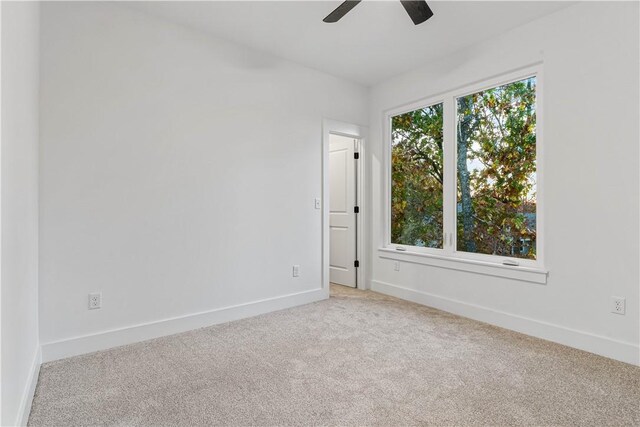 spare room featuring a ceiling fan, baseboards, and light carpet