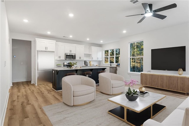 living room with baseboards, recessed lighting, ceiling fan, and light wood-style flooring