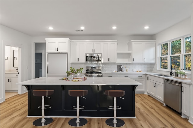 kitchen with a breakfast bar, stainless steel appliances, a center island, and light wood-type flooring