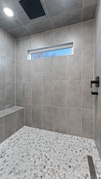 bathroom with tiled shower and a healthy amount of sunlight