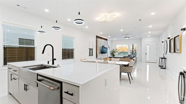 kitchen featuring white cabinets, sink, decorative light fixtures, a kitchen island with sink, and stainless steel appliances