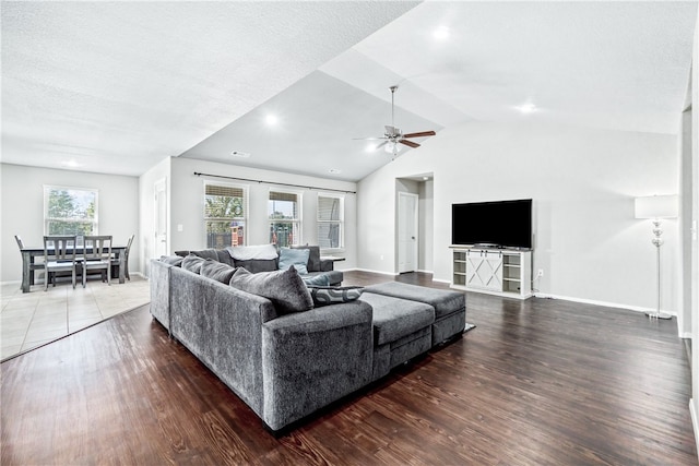 living room with ceiling fan, a textured ceiling, lofted ceiling, and dark wood-type flooring