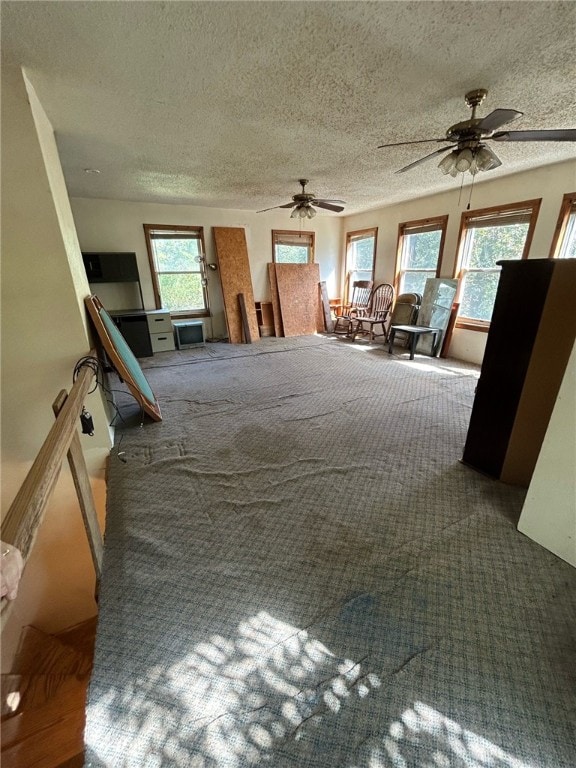 interior space featuring multiple windows, a textured ceiling, and ceiling fan