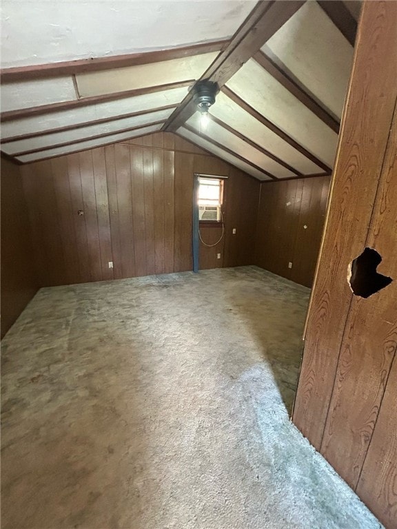 bonus room with wooden walls and lofted ceiling with beams