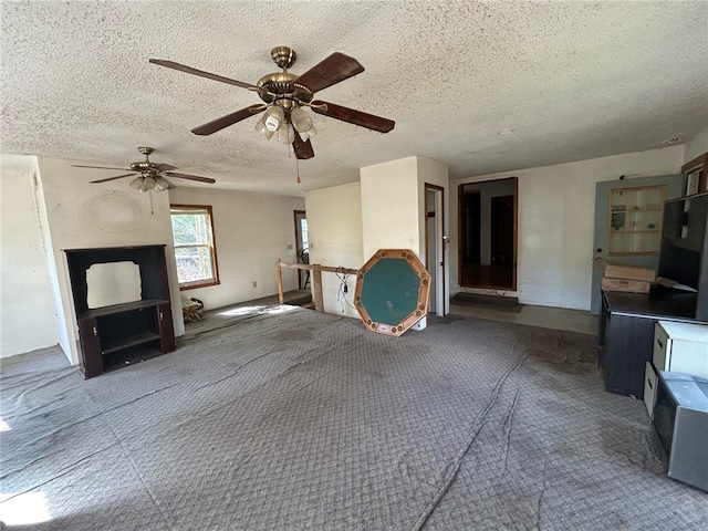 unfurnished living room with a textured ceiling and ceiling fan